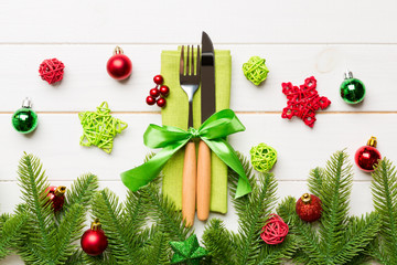 Top view of christmas decorations on wooden background. Fork and knife on napkin tied up with ribbon and empty space for your design. New year pattern concept