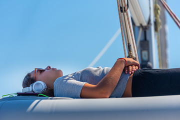 cute girl with sunglasses and headphone relaxing on a yacht