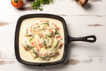 Handmade color ravioli pasta; Multi-colored ravioli pasta in a black iron pan, on wooden white table background.