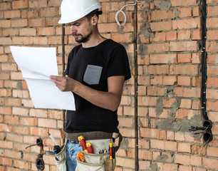 Builder handyman with construction tools, looking at the drawings on the construction site.