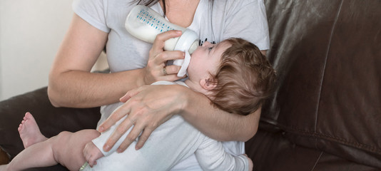 Obraz na płótnie Canvas Mom feeds a newborn baby formula from a bottle.