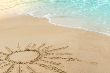 Sun drawn on seashore sand and wave with foam