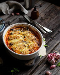 baked eggplant rolls with tomato sauce, melted cheese in white ceramic oval baking pan