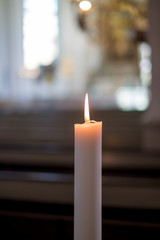 One single candle light in the church. A lot of background blur