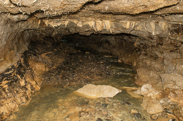 Zigzag karst cave. Incrustations of calcite and underground river on the cave.