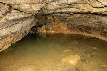 Zigzag karst cave. Incrustations of calcite and underground river on the cave.