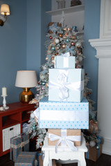 Boxes tied with ribbons one on one against the background of a Christmas tree in gentle blue tones. Symbol of congratulations and gifts for the New Year and Christmas.