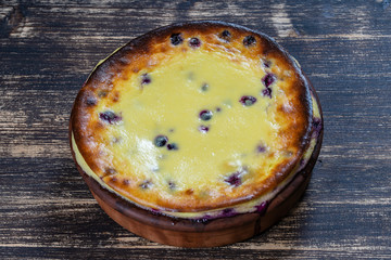 Sweet cottage cheese casserole with black currant and semolina on wooden table. Ceramic bowl with baked cottage cheese casserole