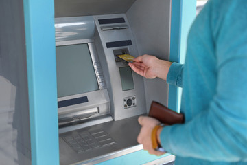 Young man using modern cash machine outdoors, closeup