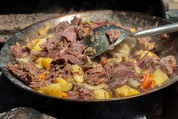 Veal with vegetables in a wоk cooked on a fire in a mobile kitchen. 