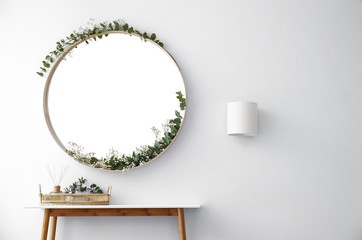Round mirror and table with accessories near white wall in modern room interior - obrazy, fototapety, plakaty