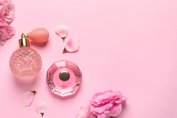 Flat lay composition with perfume bottles and flowers on light pink background, space for text