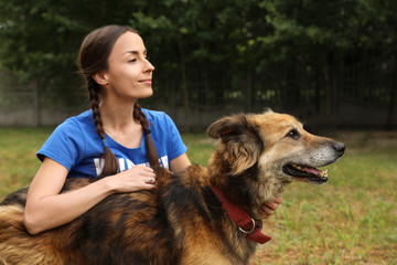 Female volunteer with homeless dog at animal shelter outdoors