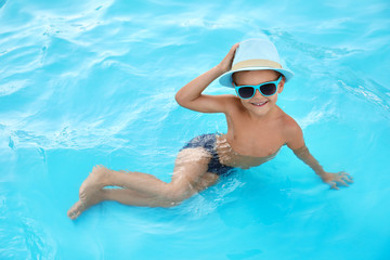 Fototapeta na wymiar Cute little boy in outdoor swimming pool