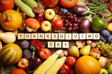 Cubes with phrase THANKSGIVING DAY, autumn fruits and vegetables on wooden background, flat lay. Happy holiday