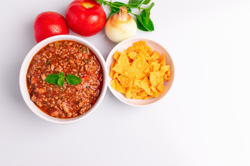 Bolognese (also know as Bolognesa or Bolonhesa) sauce and corn chips nachos in a white bowl isolated in white background, soft light, studio photo, copy space