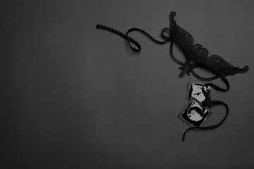 Lace mask and condoms on black background, top view with space for text. Sex game