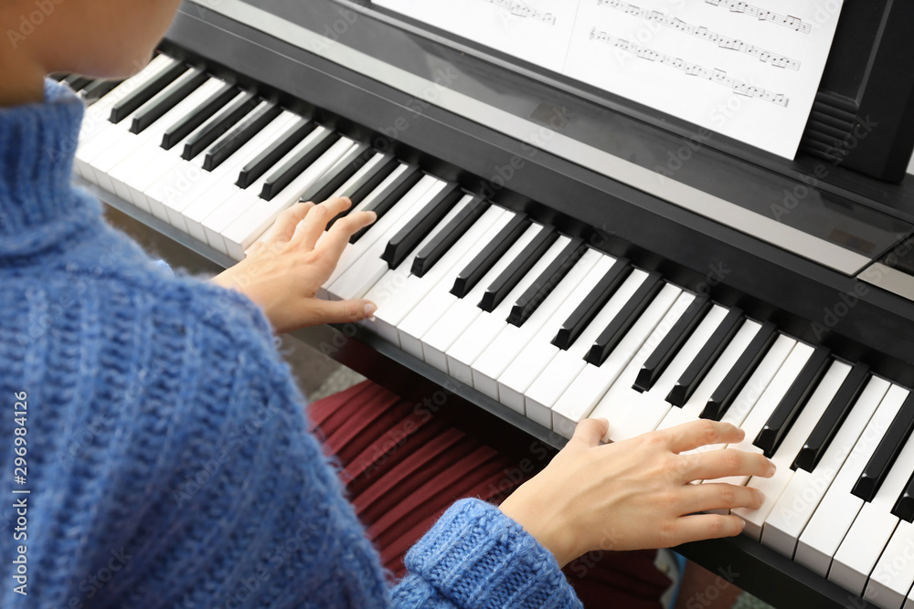 Poster Young woman playing piano at home, above view