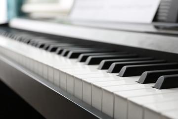 Modern piano with music sheets in room, closeup