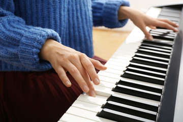 Fototapeta premium Young woman playing piano at home, closeup