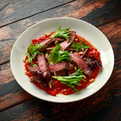 Beef Steak with Romesco sauce, nuts and vegetables on white plate