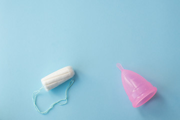 Protection for female hygeine. menstrual cup and tampon on blue background, copy space. Best way for woman menstrual protection.