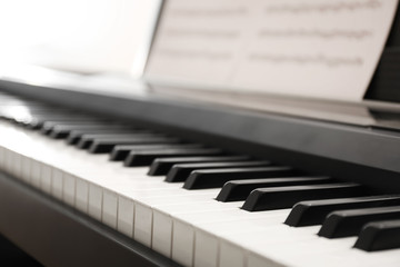 Modern piano with music sheets in room, closeup