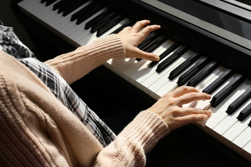 Young woman playing piano at home, closeup