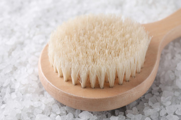 White sea salt for spa scrubbing procedure and brush, closeup