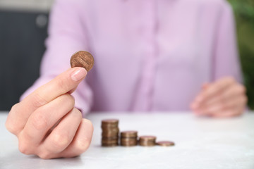 Woman holding coin at light table indoors, closeup
