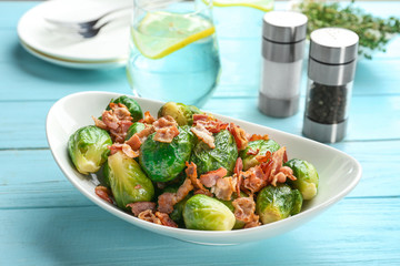 Tasty roasted Brussels sprouts with bacon on light blue wooden table