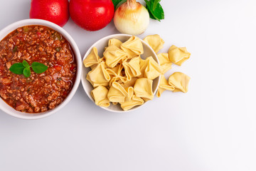 Fagottini Tortellini pasta with Bolognese (also know as Bolognesa or Bolonhesa) sauce in a white bowl isolated in white background, soft light, studio photo, copy space