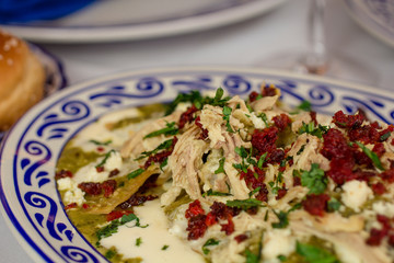 Traditional green sauce chilaquiles with shredded chicken served on elegant Talavera pottery—authentic Mexican family dining with a touch of luxury.