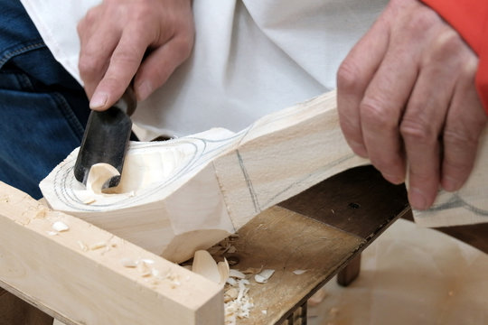 Making a wooden spoon. Men's hands with a tool closeup. Traditional handicraft woodworking or hobby.