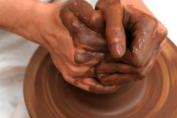 Work with clay on a pottery wheel. Close-up of female or male hands. Craft. Handwork. Shallow depth of field. Selective focus.