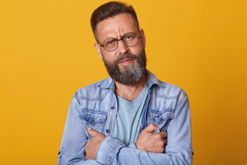 Isolated studio shot of young handsome bearded hipster man wearing trendy denim jacket, looking...