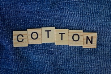 word cotton made of wooden letters on blue fabric clothes