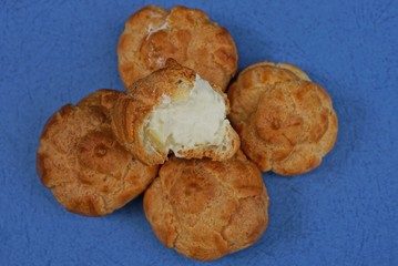 heap of brown donuts with white cream on a blue table