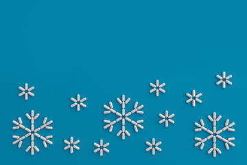 A lot of pills scattered on a blue background in the form of snowflakes . 3D illustration