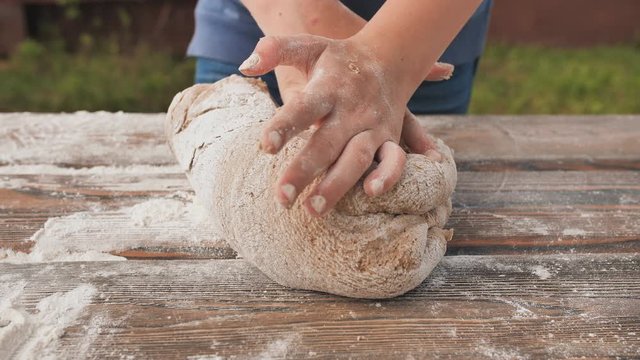 Girl hands in flour closeup kneading dough on table