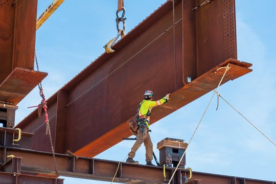 Steel worker positioning a steel girder with 3 meter wide flange on temporary supports to bolt in the next section of bridge girder.