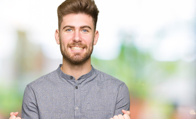 Naklejka premium Young handsome business casual man celebrating surprised and amazed for success with arms raised and open eyes. Winner concept.
