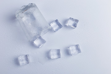 Empty inverted fallen glass with ice, on a white background.