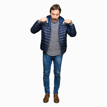 Middle age handsome man wearing winter coat Pointing down with fingers showing advertisement, surprised face and open mouth