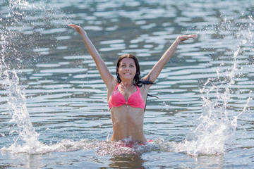 Girl in pink bikini playing in seawater