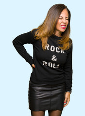 Beautiful middle age woman wearing rock and roll sweater Suffering of backache, touching back with hand, muscular pain