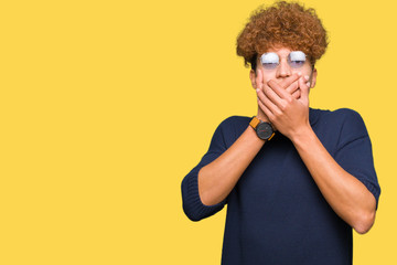 Young handsome man with afro wearing glasses shocked covering mouth with hands for mistake. Secret concept.