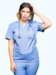 Young adult doctor woman wearing medical uniform confuse and wonder about question. Uncertain with doubt, thinking with hand on head. Pensive concept.