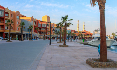 Obraz premium Hurghada, Egypt. Promenade and harbor in the Red Sea. View of embankment with houses, moored yachts and mosque.
