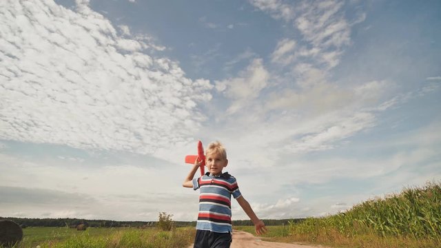 A little boy runs and launches a paralon toy airplane.